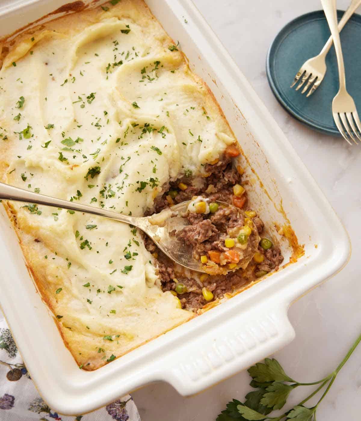 Overhead view of a baking dish with shepherd's pie with a serving scooped out.