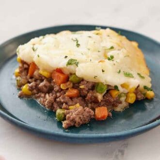 A plate with a serving of shepherd's pie with parsley sprinkled on top.
