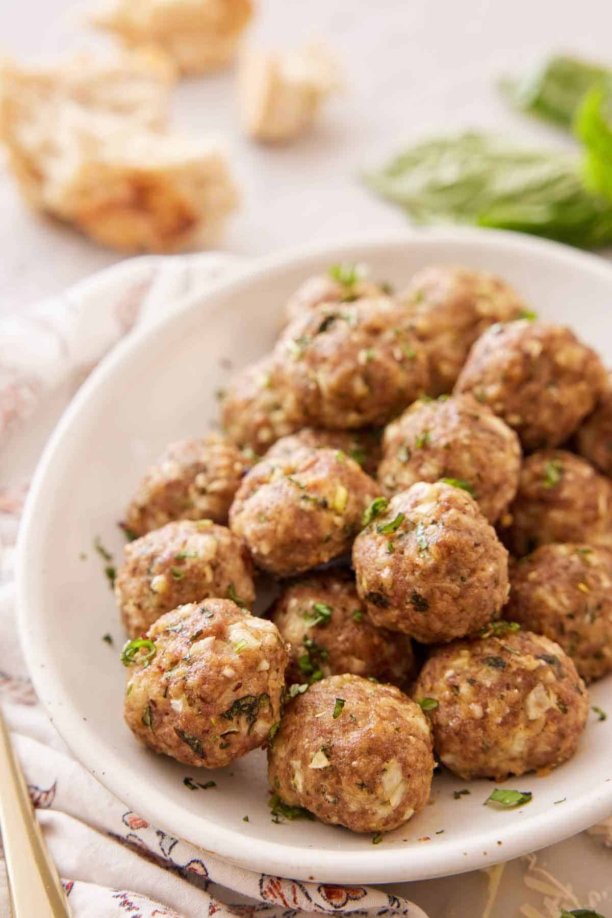 A platter of turkey meatballs with chopped herb garnish on top.