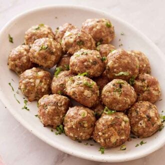 A platter of turkey meatballs with chopped basil on top.