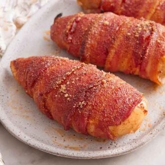 A close up view of three bacon wrapped chicken on an oval platter.