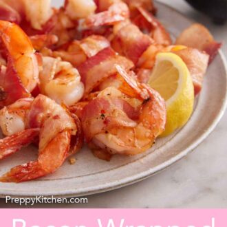 Pinterest graphic of a close view of a plate of bacon wrapped shrimp with a lemon wedge.