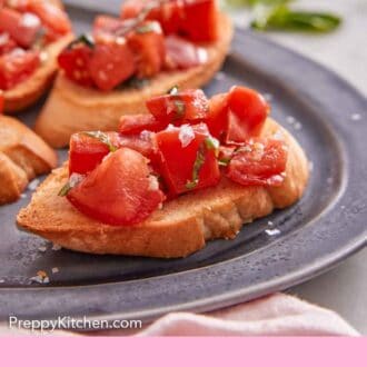 Pinterest graphic of a close-up side view of bruschetta on a platter, showing the tomato mixture piled on top of the bread.
