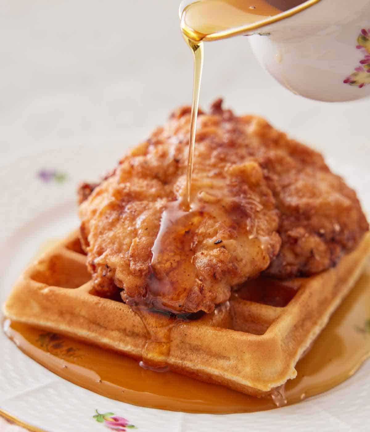 Maple syrup drizzled over a plate of chicken and waffles.