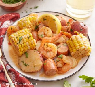 Pinterest graphic of a plate with a serving of shrimp boil with fresh parsley on top.