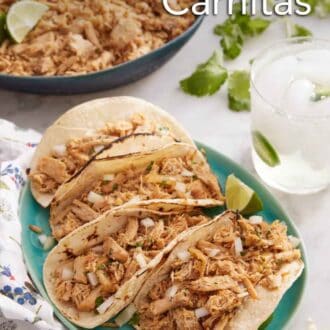 Pinterest graphic of a large plate with four tortillas holding slow cooker carnitas with an iced drink and more carnitas in the back.