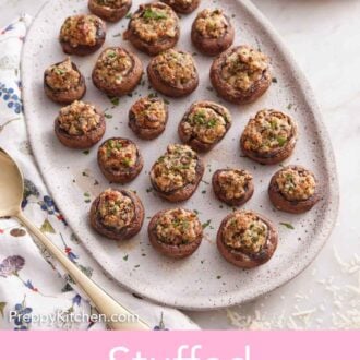 Pinterest graphic of an overhead view of an oval platter of stuffed mushrooms with chopped parsley sprinkled on top.