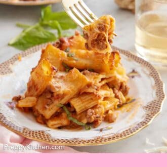 Pinterest graphic of a bite of baked rigatoni lifted from the plate with a fork.