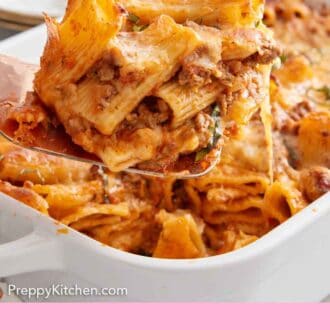 Pinterest graphic of a serving spoon scooping out a serving of baked rigatoni from a baking dish.