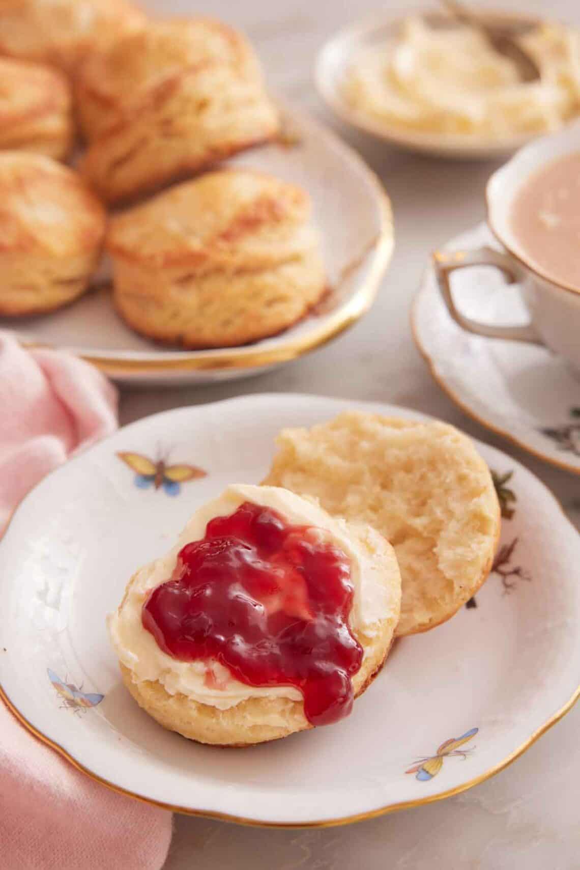 A plate with a buttermilk biscuit cut in half with butter and jam spread on top.