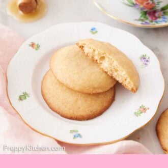 Pinterest graphic of two and a half honey cookies on a plate with a cup of coffee in the background.