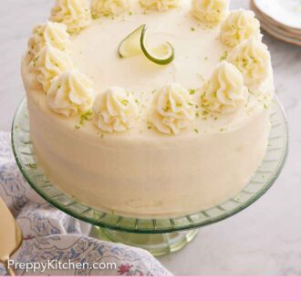 Pinterest graphic of a key lime cake on a cake stand with a lime garnish on top along with dollops of frosting with lime zest.