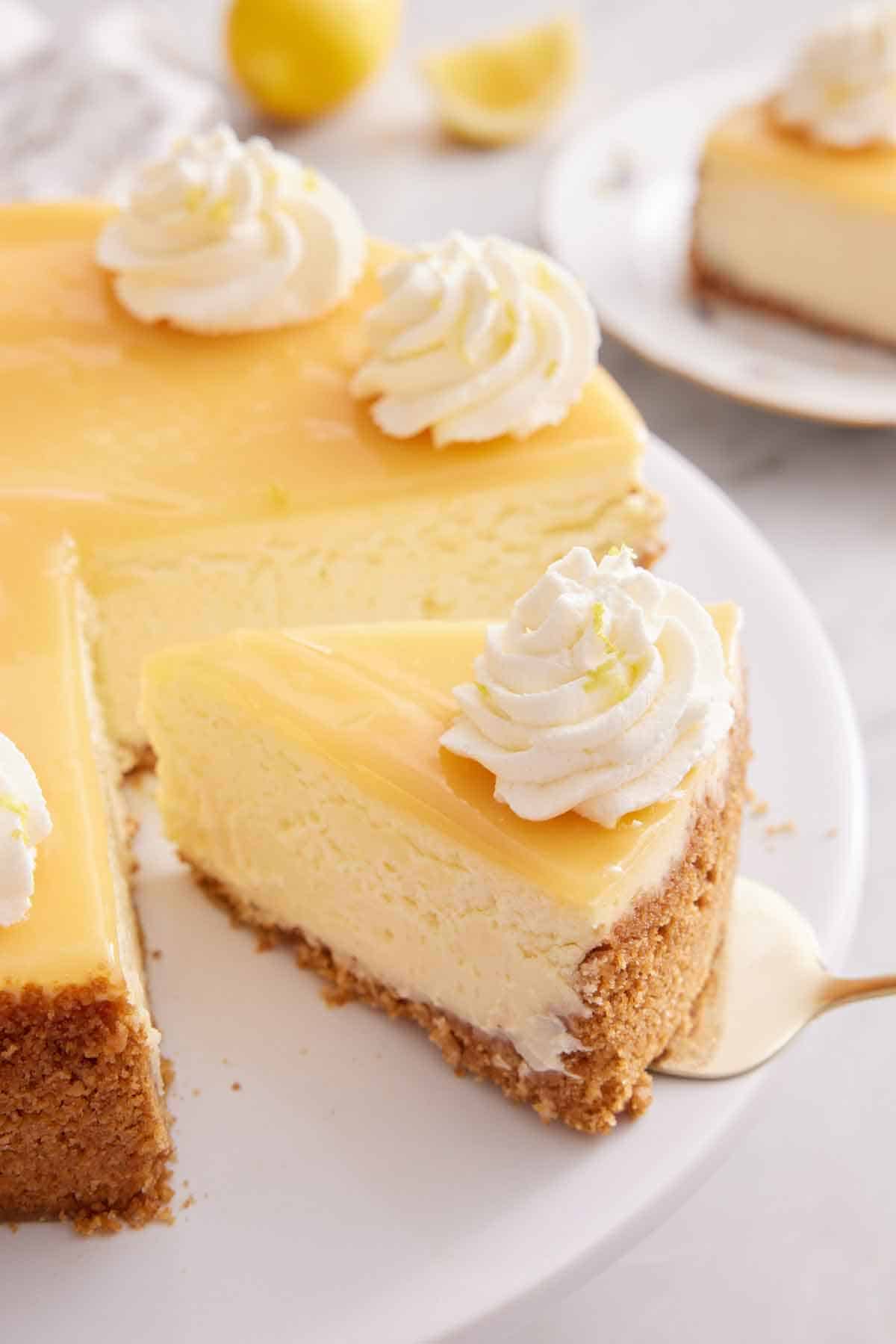 A slice of lemon cheesecake with a spatula tucked underneath pulled from the rest of the cake.