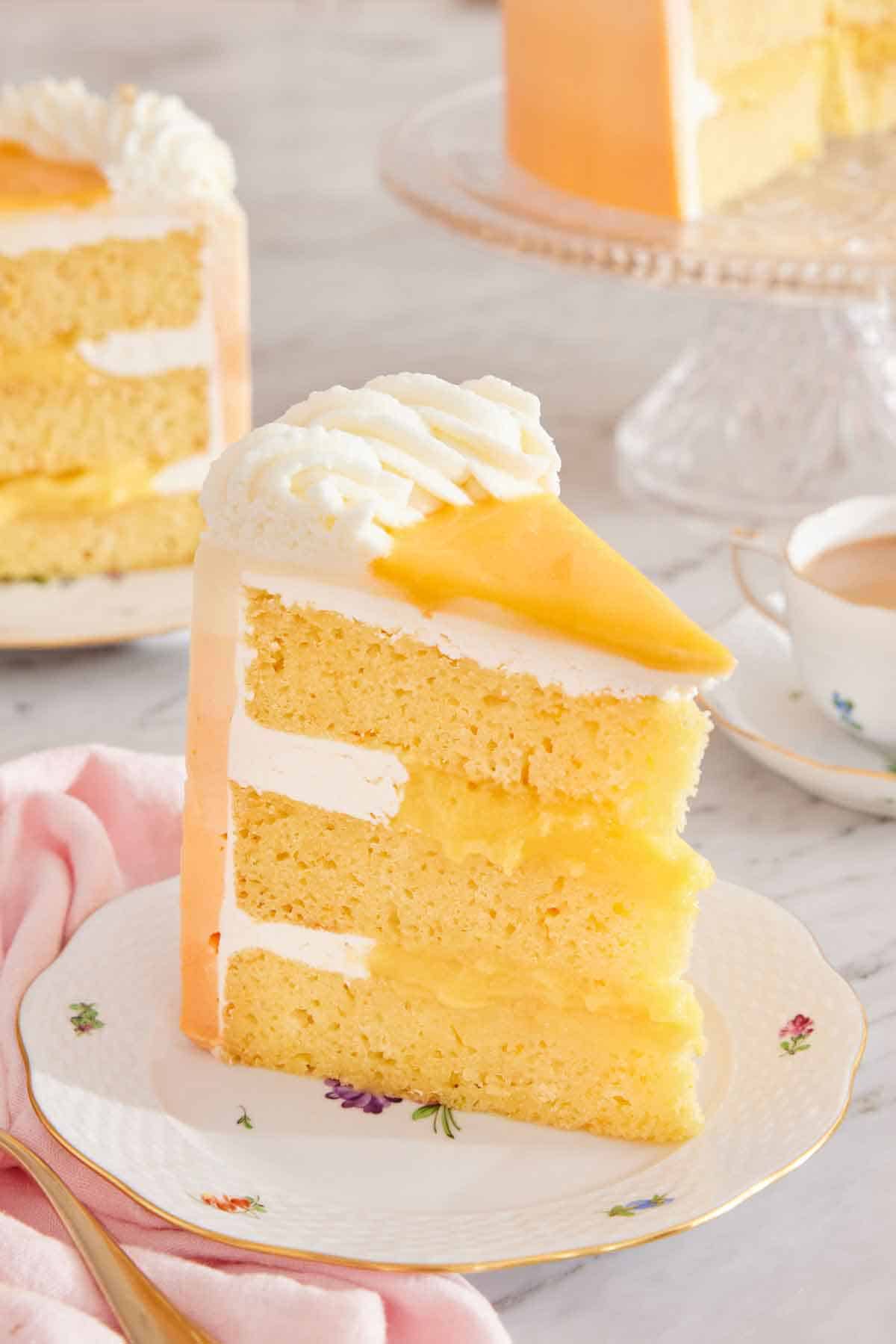 A slice of orange creamsicle cake on a plate, showing the three cake layers with frosting and orange curd in between.