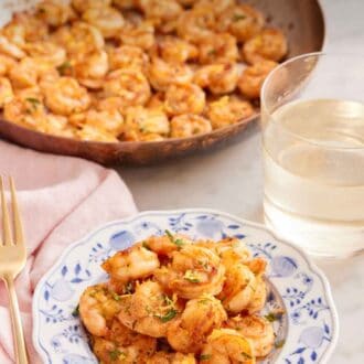 Pinterest graphic of a plate of sautéed shrimp with a glass of wine and skillet on shrimp in the background.