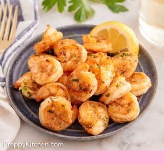 Pinterest graphic of a plate of sautéed shrimp with a slice of lemon. Wine and parsley in the background.