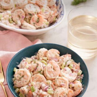 Pinterest graphic of a bowl of shrimp salad with a glass of wine and platter of shrimp in the background.