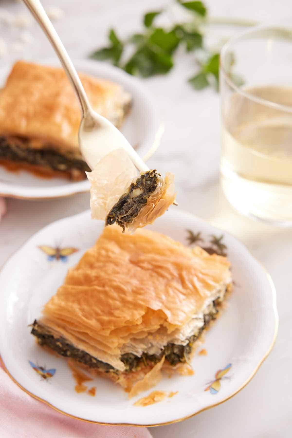 A plate of spanakopita with a forkful lifted up.