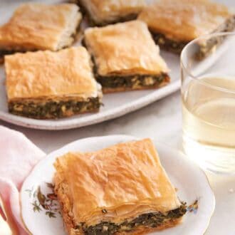 Pinterest graphic of a plate with a piece of spanakopita.