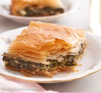 Pinterest graphic of a serving of spanakopita with a bite taken out of the corner.