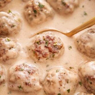 A spoon tucked under a Swedish meatball in a skillet.