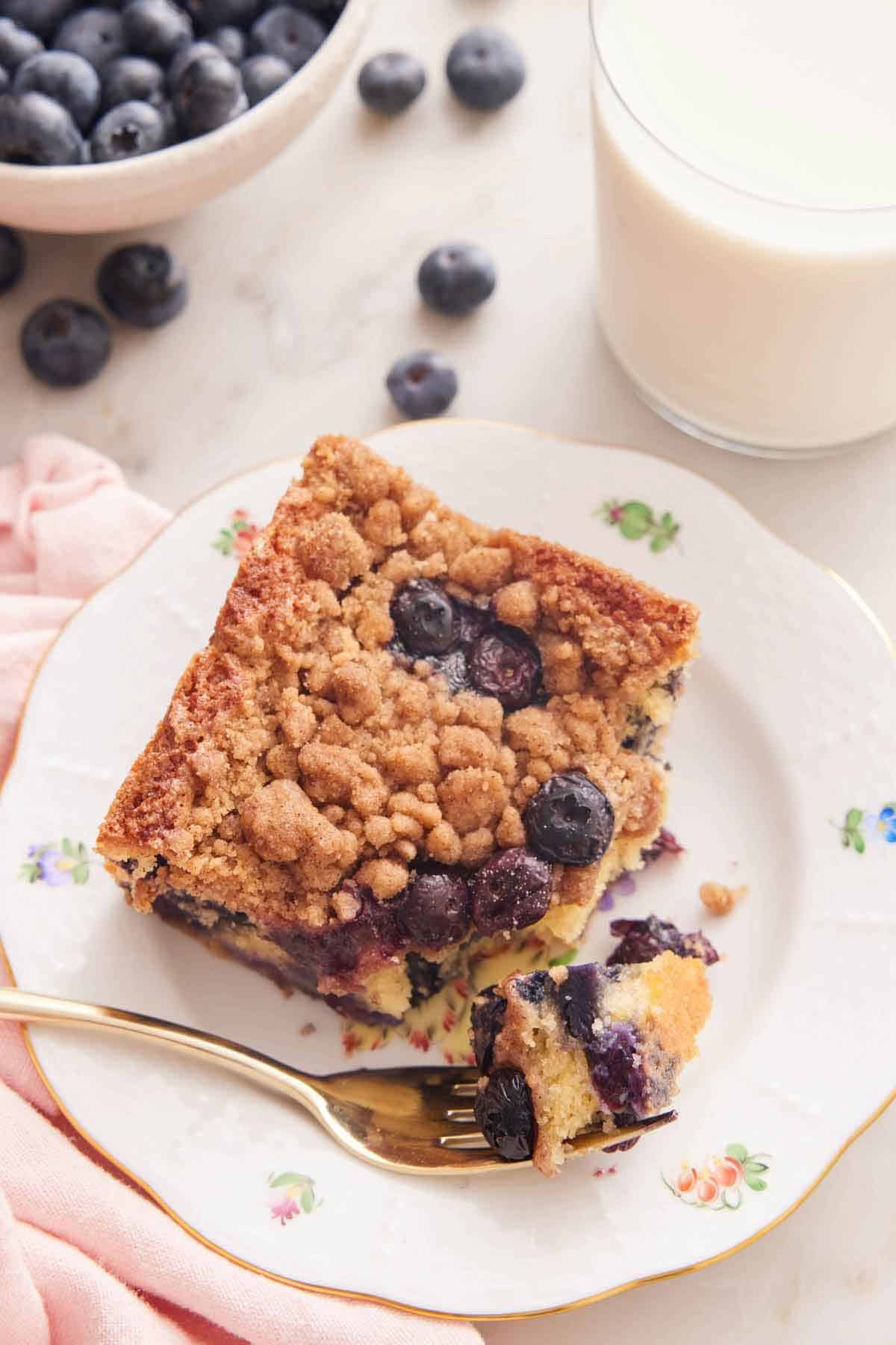 A plate with a piece of blueberry buckle with the corner bit on a fork.