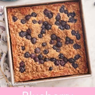 Pinterest graphic of an overhead view of a blueberry buckle in a square baking pan with two forks and some fresh blueberries off to the side.