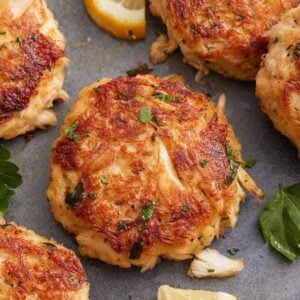 Overhead view of golden, crispy crab cakes with parsley garnishes.