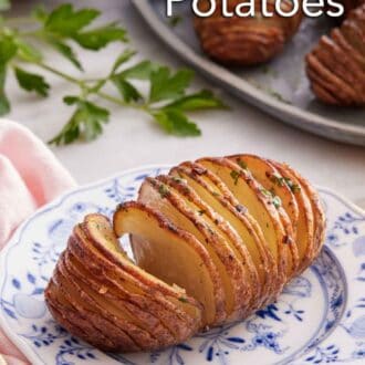 Pinterest graphic of a hasselback potato on a plate with a platter of more potatoes in the background.