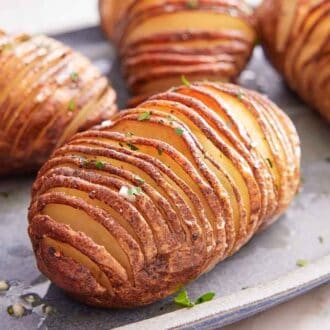 A close up view of one of multiple hasselback potatoes on a platter.