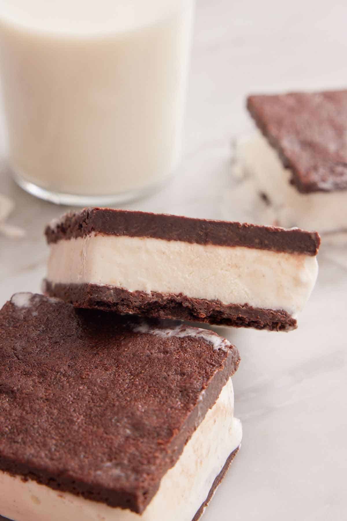 An ice cream sandwich stacked on top of another with a glass of milk in the background.