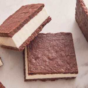 Multiple ice cream sandwiches on a marble surface with one slightly stacked on another.