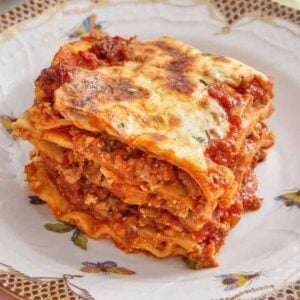 A square slice of lasagna on a plate with butterflies.
