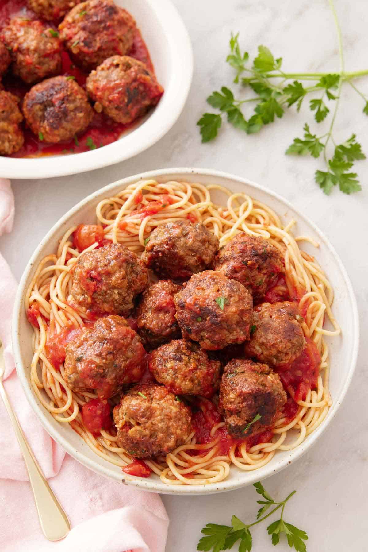 Overhead view of a bowl of spaghetti topped with meatballs and some sauce.