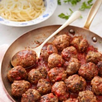 Pinterest graphic of a skillet of meatballs tossed in sauce with a spoon underneath a meatball.