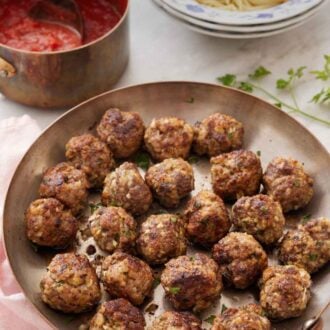 Pinterest graphic of a skillet of meatballs with a pot of tomato sauce and bowl of spaghetti in the background.