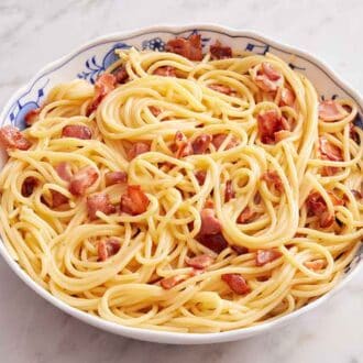 A bowl of pasta carbonara with small pieces of bacon.