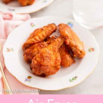 Pinterest graphic of a plate with a couple of air fryer chicken wings with a glass of ice water and a plate of more wings in the background.