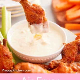 Pinterest graphic of an air fryer chicken wing dipped into a creamy white sauce.