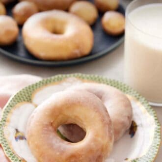 Pinterest graphic of a plate with two air fryer donuts with a glass of milk behind it and a platter of more donuts.