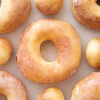 Overhead view of glazed air fryer donuts in a single layer with some donut holes.