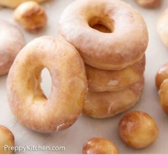 Pinterest graphic of a stack of three air fryer donuts with another leaned on it and more donuts and donut holes scattered.