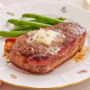 A plate of bacon wrapped filet mignon with green beans.