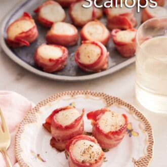 Pinterest graphic of a plate with three bacon wrapped scallops with a platter in the back along with a glass of wine.