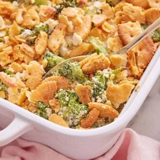 A spoon tucked into a baking dish of broccoli casserole.
