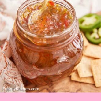 Pinterest graphic of a spoon scooping into a jar of jalapeno jelly.