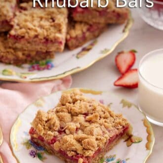 Pinterest graphic of a plate with a slice of strawberry rhubarb bar with a glass of milk and a platter of bars in the background.