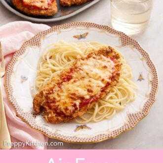 Pinterest graphic of a plate with spaghetti noodles with air fryer chicken parmesan on top. A platter with three air fryer chicken parmesan in the background.
