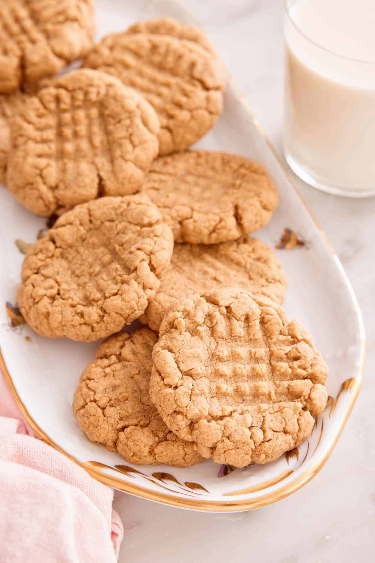 A platter with almond butter cookies with a glass of milk on the side.