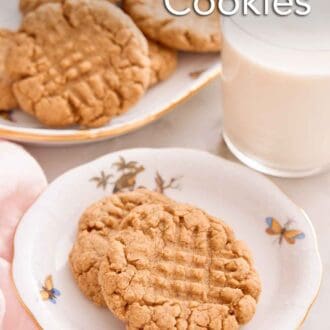 Pinterest graphic of a plate with two almond butter cookies with a platter of more cookies and glass of milk behind it.